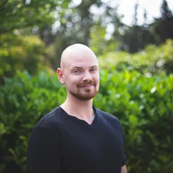 En mann som står foran en busk