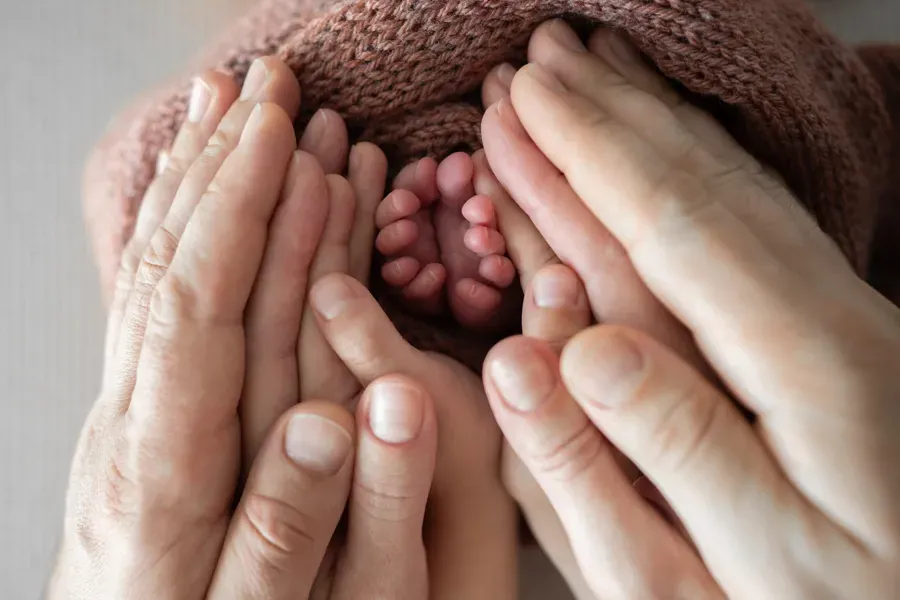 Et nærbilde av hender som holder en babys føtter