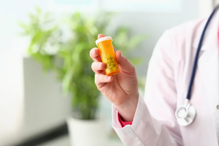 En lege holder et glass med tabletter