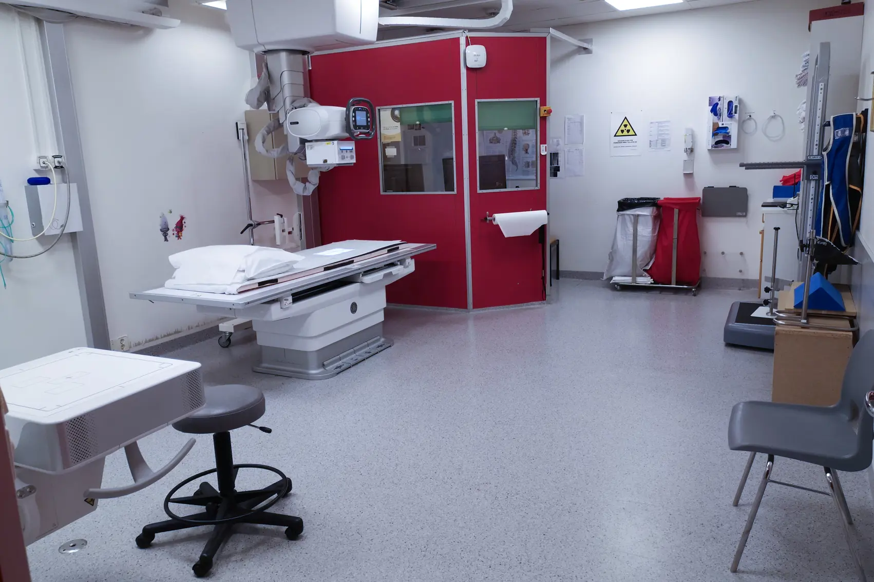Et sykehusrom med en seng og en rød dør