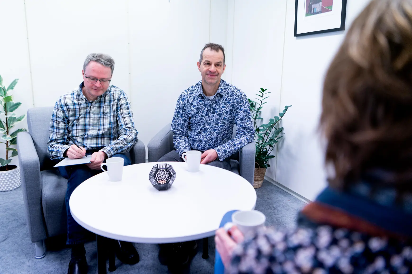 A group of men sitting around a table with cups and saucers