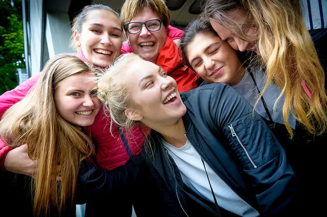 Fire lærlinger og to ledere smiler og holder rundt hverandre foto .