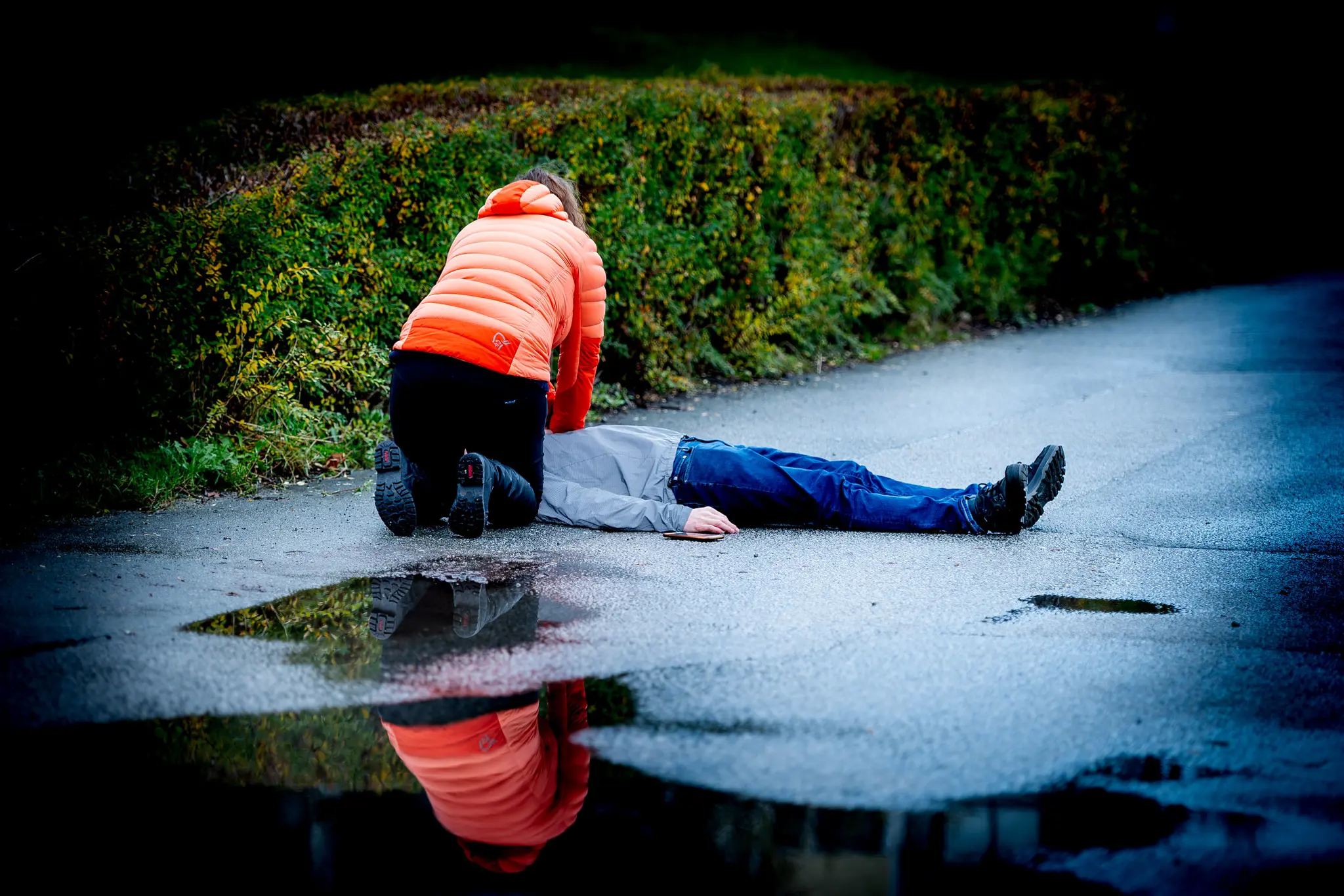 Kvinne utfører brystkompresjoner på person som ligger på bakken.