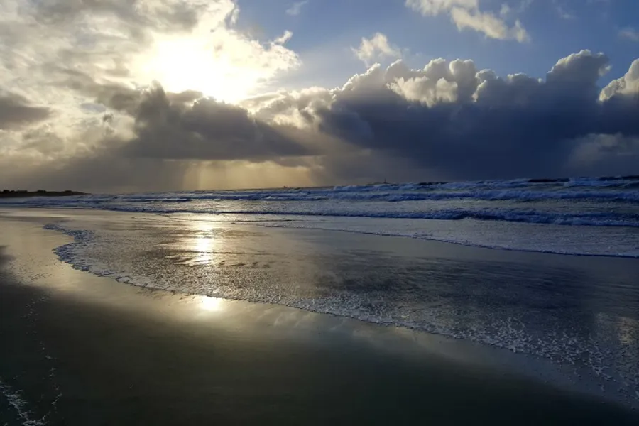 Strand i solnedgang. Bilde.