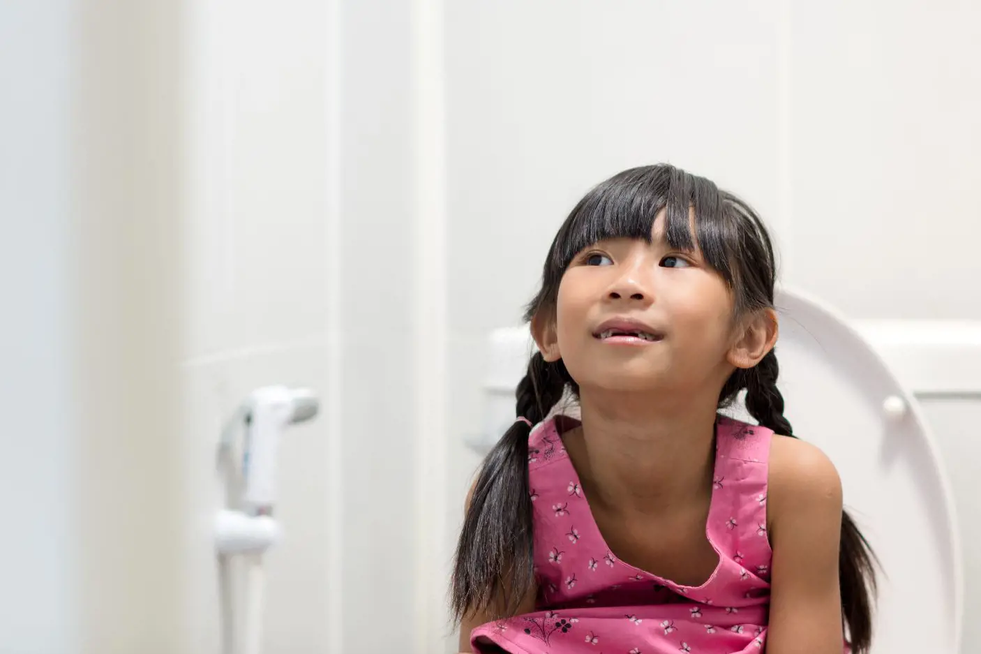En ung jente sitter på toalettet