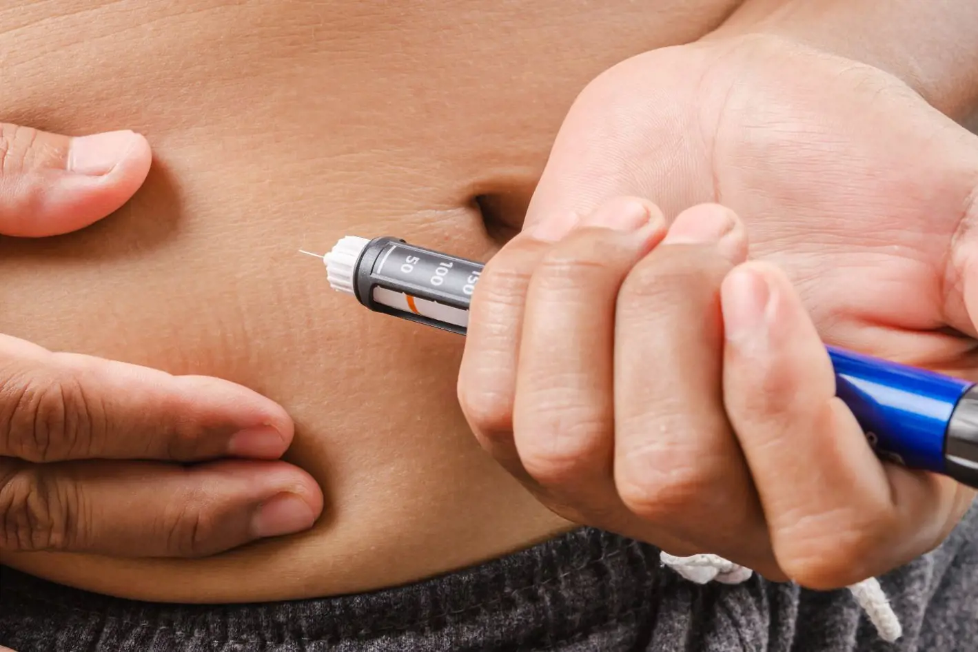 en person setter en insulinpenn i magen