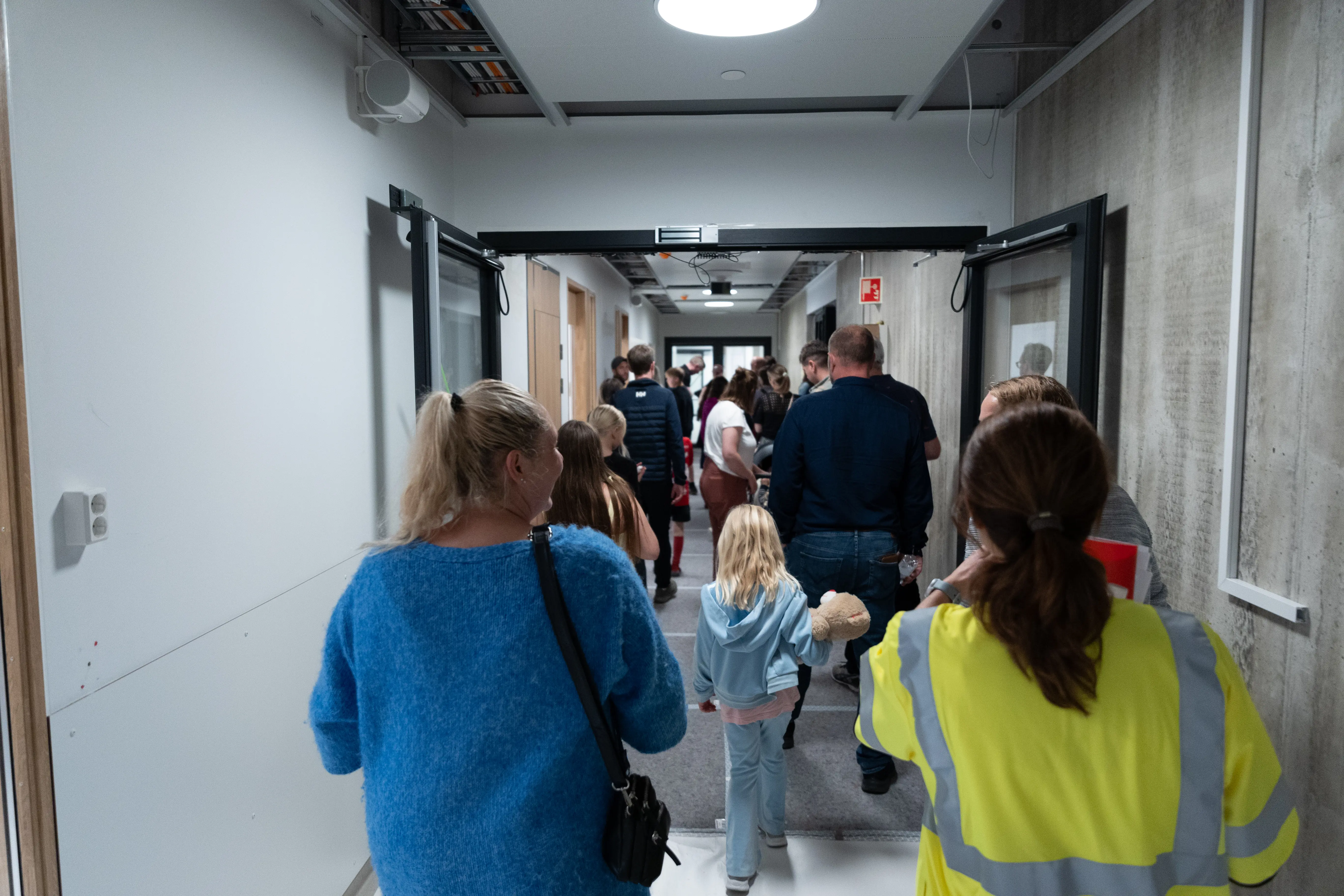 Folk som går i en gang med ryggen til.