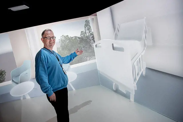 En mann peker på en digital fremstillling av en sykehusseng.