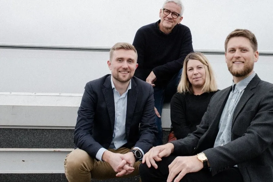 Fire ansatte i COWI og Nordic som sitter i en trapp og smiler. Foto.