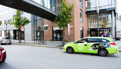 Rødt murbygg med glassgang over veien utenfor. Kjøpesenter Amfi i samme bygget.