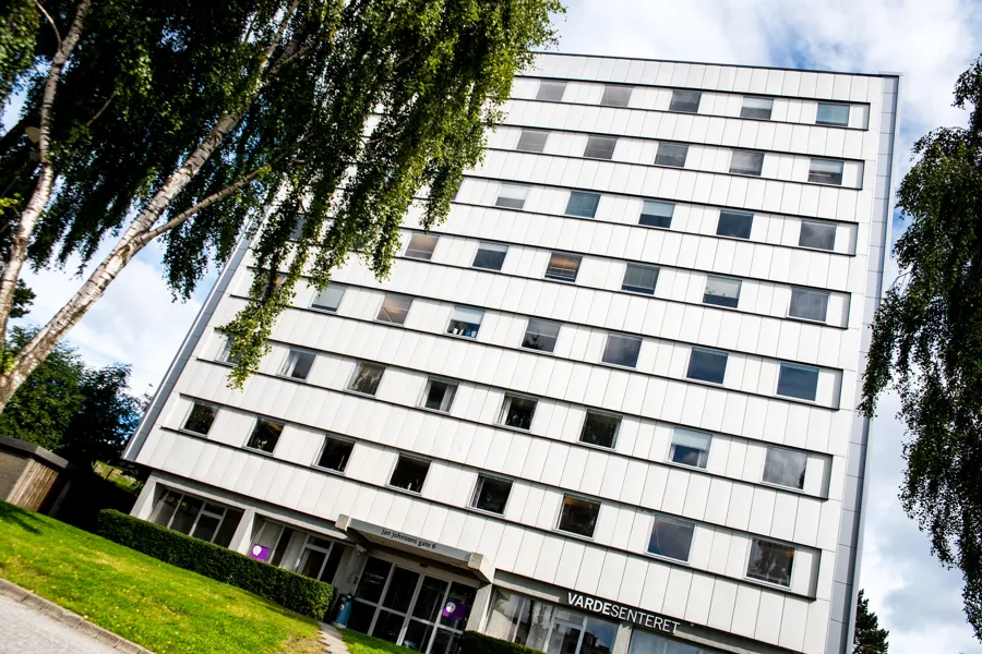 Hvitt bygg med mange vinduer. Inngang midt på.